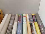 many rolls of fabric on a shelf next to a picture frame