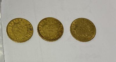 three gold coins sitting next to each other on a white surface