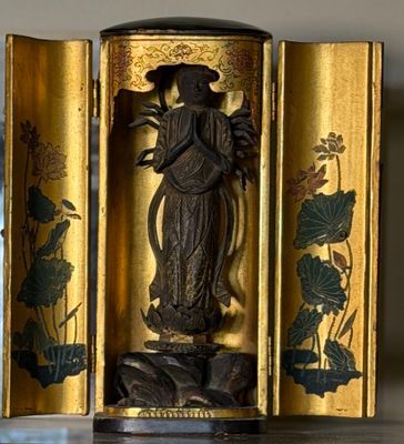a gold case with a statue of a woman holding a flower
