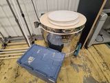 une image représentant un seau muni d'un couvercle posé sur un plancher en bois