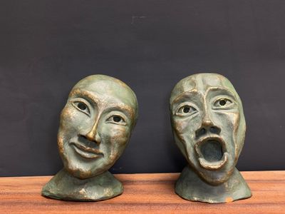 pair of bronze sculptures of two faces with open mouths