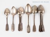 six silver spoons are lined up in a row on a white surface