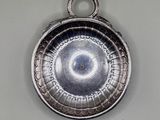 a silver plate with a circular design hanging on a wall