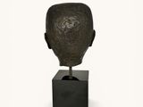 sculpture of a man ' s head on a black stand