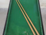 a pool table with two cues and a ball on it
