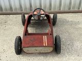 a small red pedal car with a steering on the ground