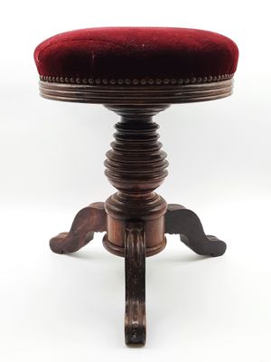 un vieux tabouret sur lequel est posé un coussin rouge