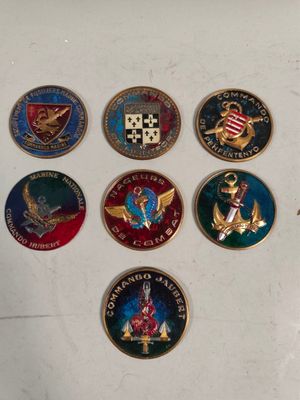 Plusieurs insignes militaires sont disposés sur un fond blanc