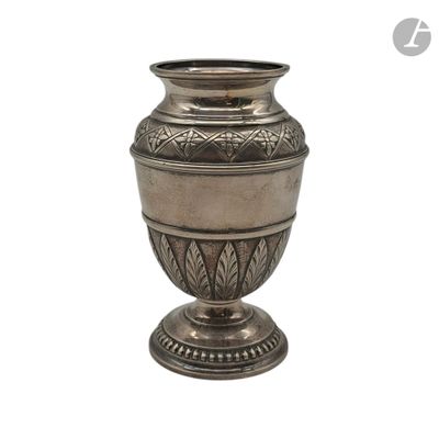 un vase en argent posé sur une surface blanche