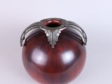 a wooden vase with metal handles on a white surface