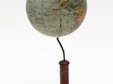 un petit globe terrestre posé sur un socle en bois, avec un fond blanc