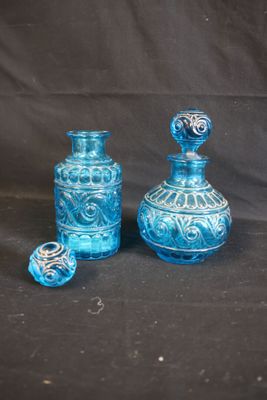 two blue glass vases sitting next to each other on a black background