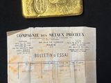 an old gold bar sitting on top of a piece of paper next to a piece of paper