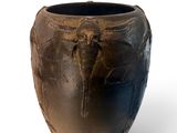a black vase with a bird on it on a white surface