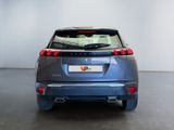 the rear end of a blue car in a room with a white wall