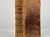 an old book sitting on top of a white table next to a white wall
