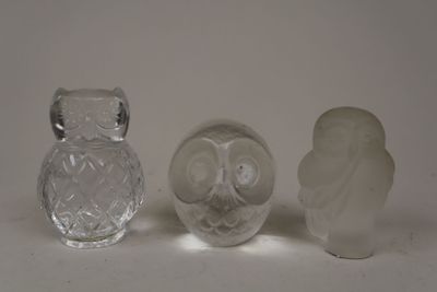 trois figurines de chouettes en verre posées les unes à côté des autres sur une surface blanche