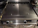 une plaque de cuisson en acier inoxydable dans une cuisine professionnelle, avec des casseroles et des poêles posées dessus