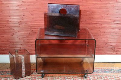 une table en verre sur laquelle est posé un livre, à côté d'une valise