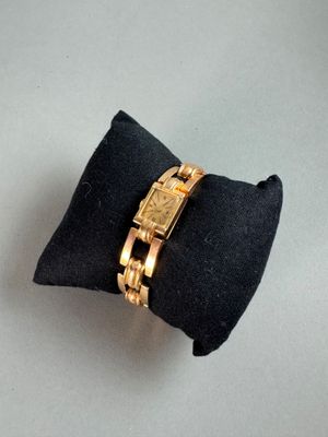 a gold watch sitting on top of a black pillow