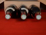 three bottles of wine in a wooden box on a red table