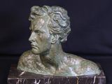 bronze bust of a man on a marble base with a black background
