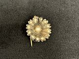 a close up of a gold flower brooch on a black surface