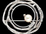 broche en argent ornée d'une perle au centre d'un cercle