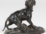 une image représentant une statue en bronze d'un chien assis sur un rocher
