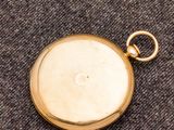 une vieille montre de poche en or, avec une chaîne suspendue sur le côté
