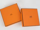 two orange boxes with black trims are open on a white surface