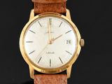 a gold wrist watch with a brown leather strap