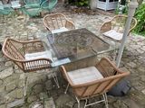 a glass table with four chairs around it on a stone patio