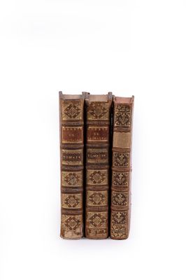 three old books sitting on top of each other on a white surface