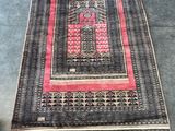 un tapis noir et rose avec une bordure rouge posé au sol