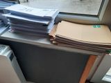 a stack of papers sitting on top of a desk next to a window