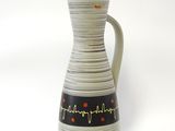 un vase blanc orné de motifs noirs et rouges