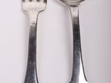 two spoons and a fork on a white surface