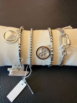 trois bracelets et une bague posés sur un coussin, avec une étiquette de prix