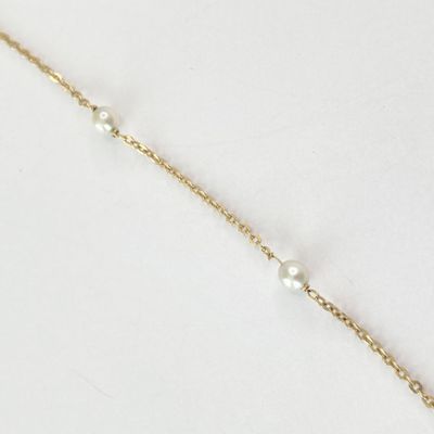 un bracelet en chaîne d'or orné de perles sur fond blanc