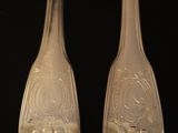 pair of silverware spoons on a black surface with a black background