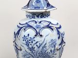 un vase bleu et blanc surmonté d'un oiseau
