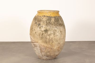 un vase posé par terre devant un mur blanc