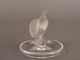 a glass bird that is sitting on a glass plate