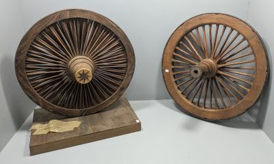 deux vieilles roues en bois exposées dans une pièce