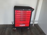 une armoire à outils rouge et noire posée sur un parquet en bois massif