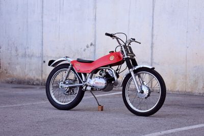 a red motorcycle parked in a parking lot next to a white wall