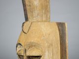 a close up of a wooden mask on a white surface