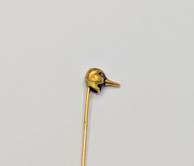a gold stick with a bird on it on a white surface