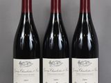 three bottles of red wine are lined up on a table